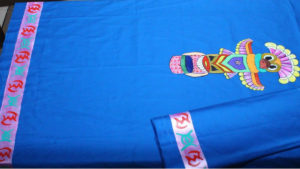 Totem pole and hyroglifics on a peacock colored dress material